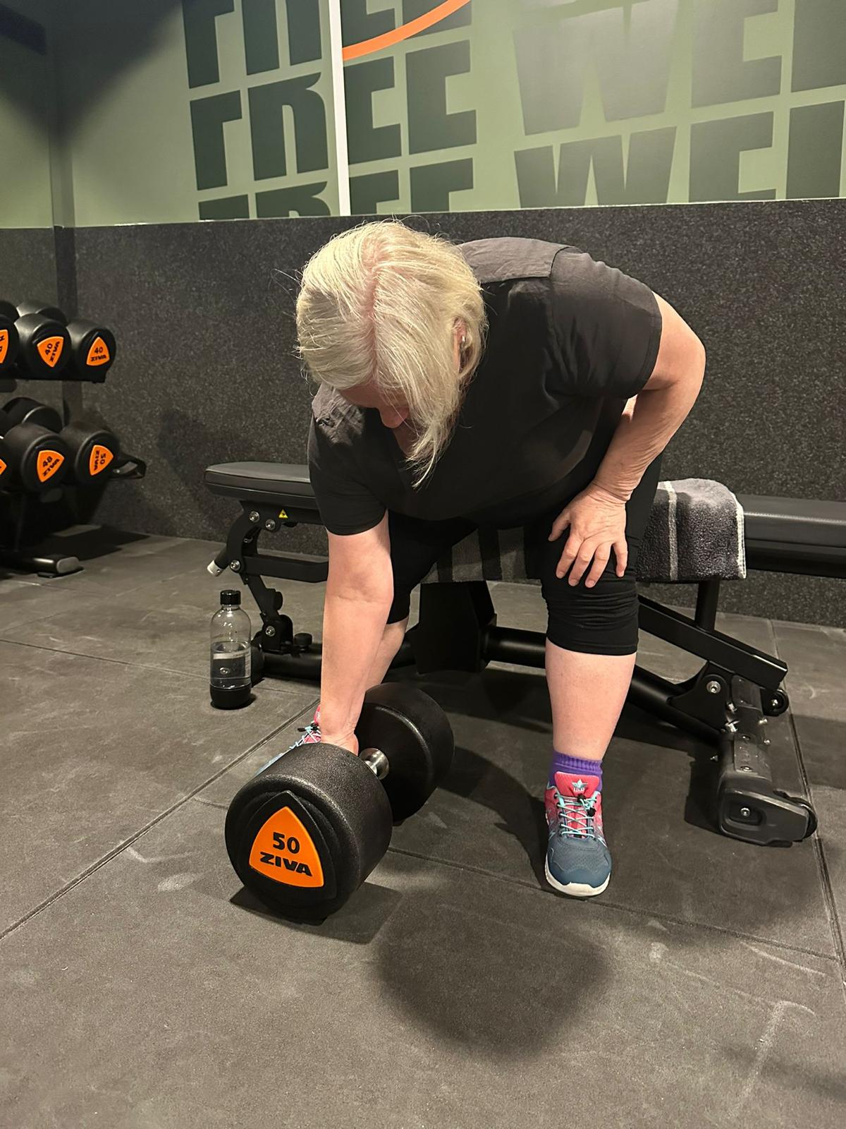 Frau beim Krafttraining mit einer Kurzhantel im Fitnessstudio